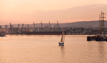 Serene evening view featuring a single sailboat cruising on tranquil waters