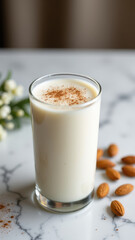 Glass of milk on a marble table with cinnamon and almonds.