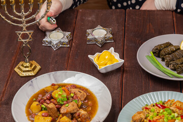 A Jewish woman's hand lights candles on Shabbat in candlesticks with a Star of David