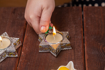 A Jewish woman's hand lights candles on Shabbat in candlesticks