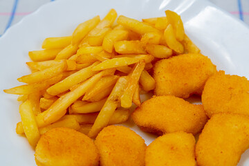 French fries and golden chicken nuggets on a plate close-up