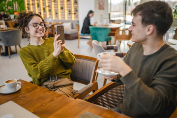 girlfriend use mobile phone to filming video of her boyfriend at cafe