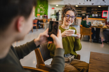 boyfriend use mobile phone to take a photo of his girlfriend at cafe