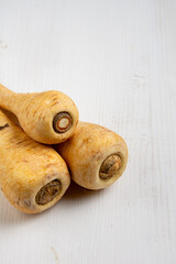 Aerial view of parsnips on white wooden table, vertical with copy space