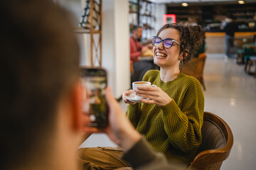 boyfriend use mobile phone to take a photo of his girlfriend at cafe