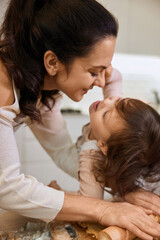 Happy mother and smiling cute little child daughter rolling dough for homemade pastry.