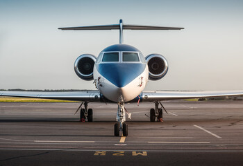 White-blue business jet facing the camera. Symmetric frontal close-up view of private T-tail...