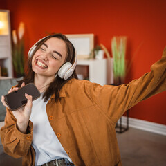 playful woman with headphones listen music ad sing in the living room