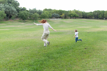 Mother and son playing tag in a sunny green park