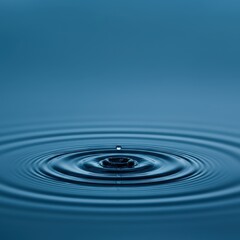 Close-up of a single water droplet creating ripples on a calm blue surface, symbolizing tranquility and nature's beauty