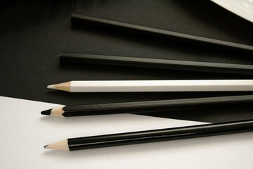 A monochrome art-themed photo featuring graphite pencils and metallic paints on a black background, creating a stylish and elegant composition.