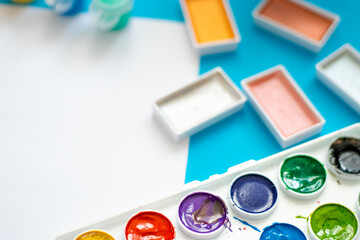 A bright and colorful photo with art supplies, including paints, pencils, crayons, and a palette on a vivid background.