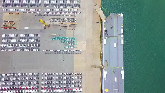 Cars parked in the parking lot are being loaded onto a car carrier to be exported to countries around the world.