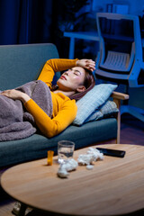Fatigued Asian woman resting on sofa, surrounding medical supplies indicating illness and discomfort
