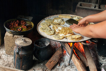 The hands of a woman cooking traditional Mexican food with firewood and a comal. Quesadillas and sopes.