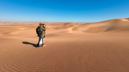 Photographer on sand dunes under blue sky