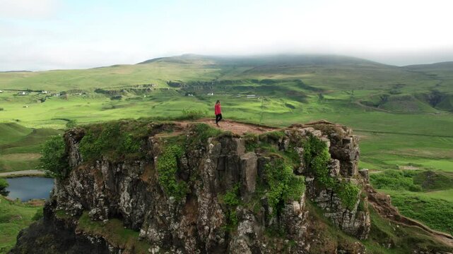 Aerial Drone Adventure Girl Walking Fairy Glen Isle of Skye Scotland in Orange Jacket On Rock Mountain