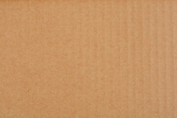 A flat surface of uniform brown cardboard fills the entire frame, showcasing its texture and color