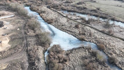 Frozen bog. A bog covered with ice in winter. Shrubs in the taiga. A country road made of mud and sand.