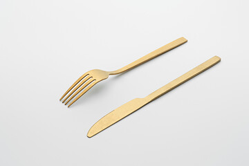 Set of golden metal cutlery on white background