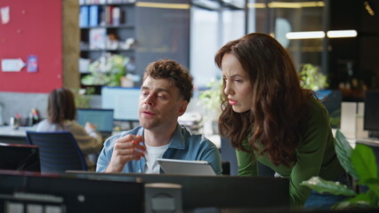 Serious office couple brainstorming task working together at computer closeup