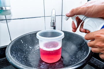 Adult Colombian Latino man mixing toiletries with spray to wash his home's bathroom