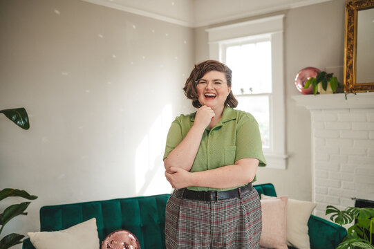 Non Binary Person smiling with hand on their chin