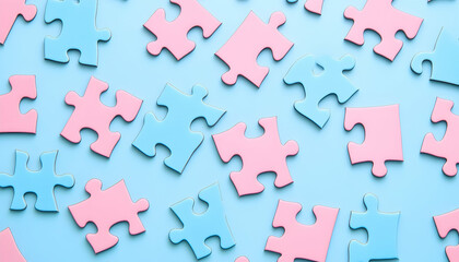 Pink and blue puzzle pieces on a blue background. The puzzle pieces are in various shades of pink and blue and are arranged in a random order. The background is a light blue color.