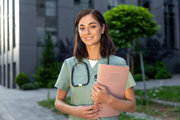 Smiling and positive young female doctor in the clinic yard