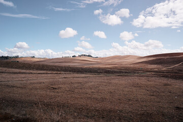 A vast, arid landscape with rolling hills under a partly cloudy sky.
