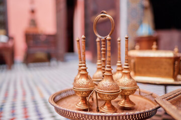 A decorative metal brass ancient jars in a traditional Moroccan style standing on vintage tray in...