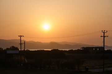Sun sets over serene mountains, casting a warm glow on tranquil waters and landscape