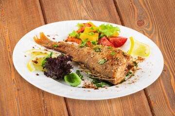 Fried tasty fish steak with cooked vegetables