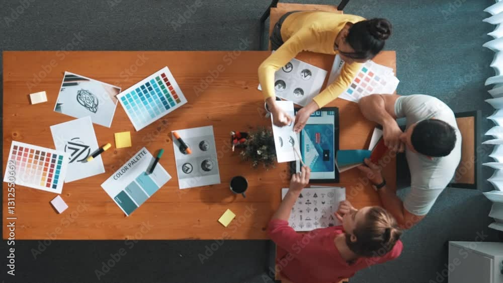 Poster top down aerial view of designer looking at tablet while project manager choosing color palettes. ti