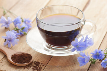 Chicory healthy drink in a glass cup with flowers on rustic wooden background, closeup, natural medicine and naturopathy concept