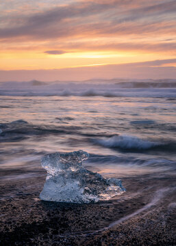 Glacier ice on Diamond Beach at sunrise with crashing waves, near Jokulsarlon, South Iceland, Iceland, Polar Regions