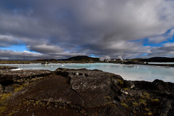 dark blue, low clouds above blue water and lava rocks in the neighborhood of Svarstsengi geothermal power plant, Iceland