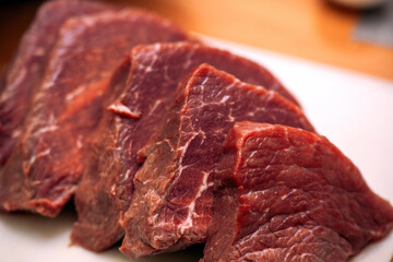 freshly cut beef steaks arranged neatly on a wooden cutting board. The rich red color of the meat highlights its quality and freshness, making it ideal for grilling or cooking