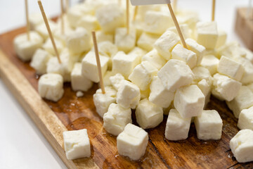 Close up shot of cubic pieces of feta cheese on wooden cutting board
