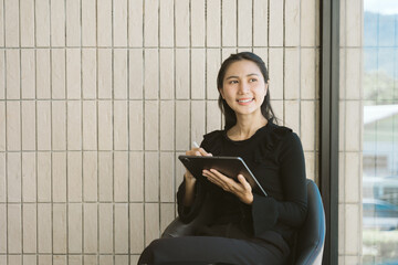 Smiling Woman with Tablet: A stylish woman is engrossed in her tablet. She has a charming smile and...