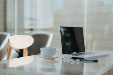 Workspace Serenity: A minimalist workspace bathed in soft, natural light, featuring a laptop, a steaming coffee cup, and a pair of earbuds, creating a sense of productivity and calm.