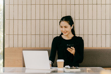 Modern Professional: A young woman focused on her laptop, phone in hand, surrounded by coffee and...