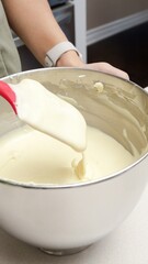 Close-Up of a Person Mixing Thick and Creamy Batter in a Stainless Steel Bowl with a Red Spatula