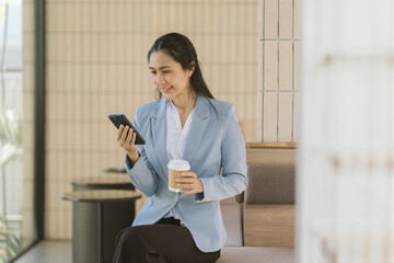 Smart Businesswoman's Moment: An elegant businesswoman, engrossed in her mobile, sips coffee,...
