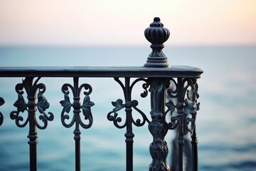 Naklejka premium Ornate metal railing overlooking a calm sea at sunset, detailed craftsmanship.