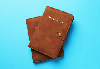 Passports in brown covers on light blue background, top view