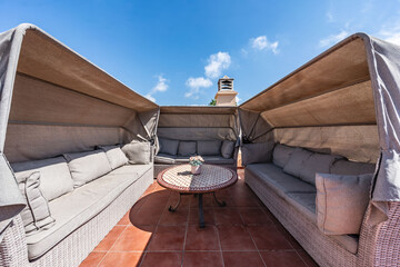 a close up image of outdoor covered sofas on sunny rooftop penthouse terrace 