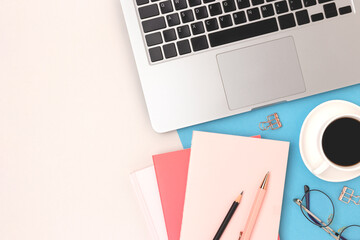 Office supplies, cup of coffee, laptop and eyeglasses on a gray and blue background. Workspace for...