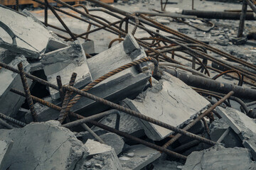 Fototapeta premium Construction site debris with concrete blocks and rusty rebar scattered across the ground during demolition activity