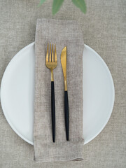 Beige napkin on a white plate. Table setting. Fork and a knife.